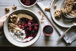 Delicious breakfast bowl with quinoa, rice and groats near tea cup and newspaper