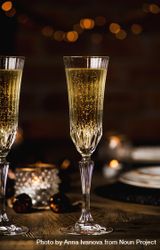 Two crystal flutes full of champagne on wooden table 48MZYb