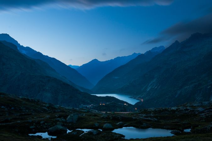 Road and lights over river in mountain valley at dusk