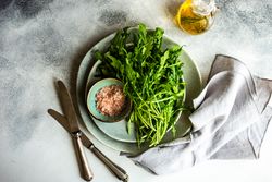 Looking down at plate with bunch of arugula and pink salt served with olive oil