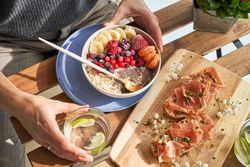 Crop faceless woman sitting at table with assorted healthy food during breakfast