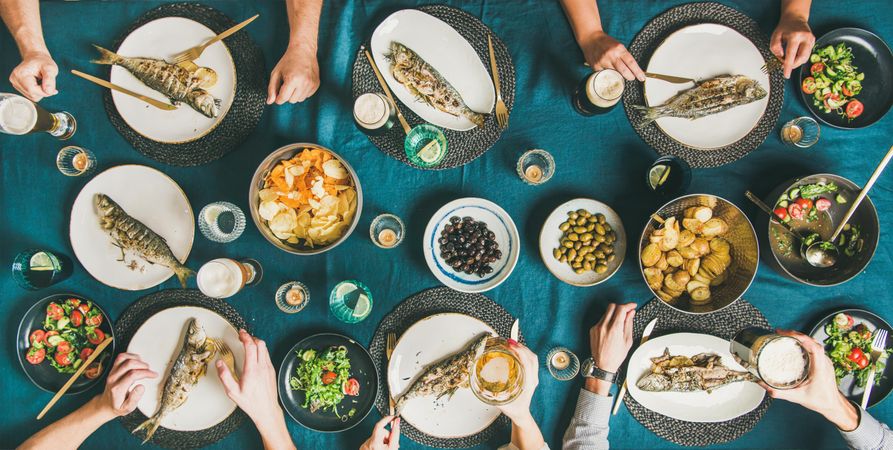 Group of people at table with whole fish on each plate and vegetable side dishes