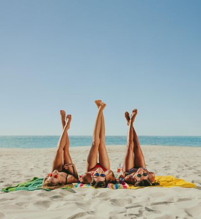 Group of women posing with legs raised to the sky at the beach