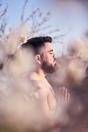 Shirtless man meditating in spring garden