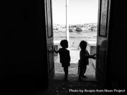 Monochrome photo of two children standing at the door in Aswan, Egypt 4OXVab