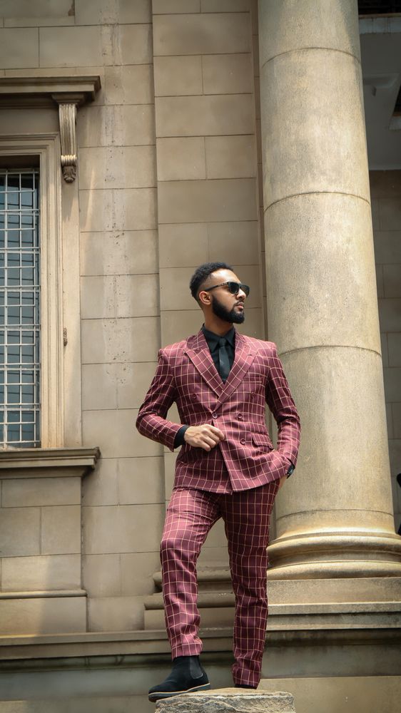 Man dressed in red suit standing outdoor beside a wall