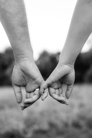Grayscale photo of two people holding hands