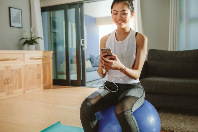 Woman listening to the music while sitting on a exercise ball at home