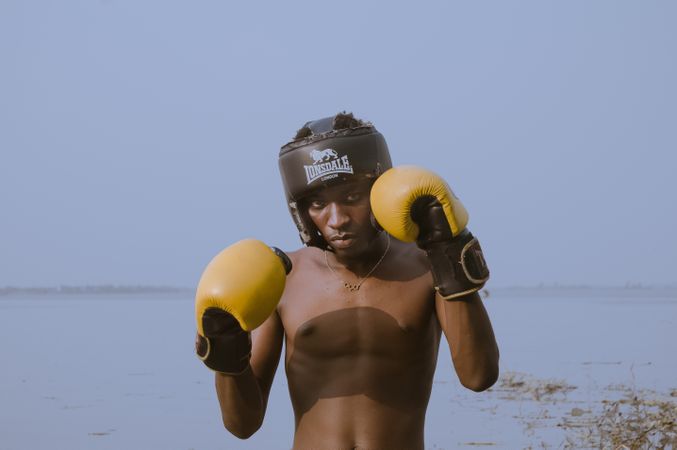 Man in wearing boxing gloves standing near lake in Accra, Ghana