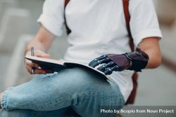 Young man with prosthetic hand holding a notebook 5rAX70
