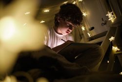 Serious boy drawing in blanket fort with garland