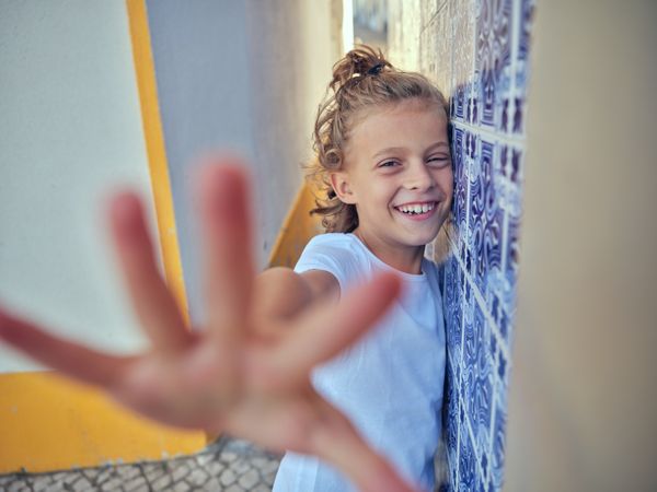Portrait of cheerful boy leaning on wall and reaching out to cam