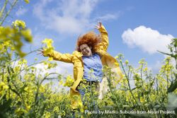 Happy red haired woman dancing in a rapeseed field 0LovEb