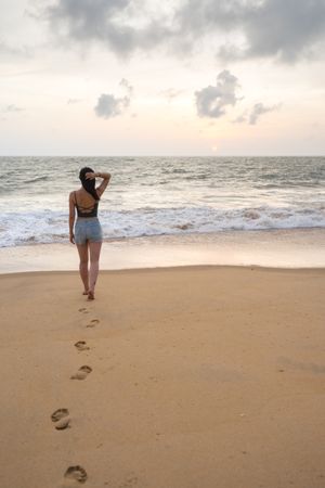 Woman in beachwear walking on sand barefoot