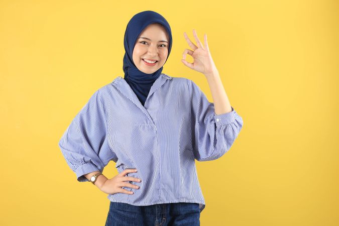 Beautiful Smiling Asian Young Woman in Blue Striped Shirt Showing Okay Gesture