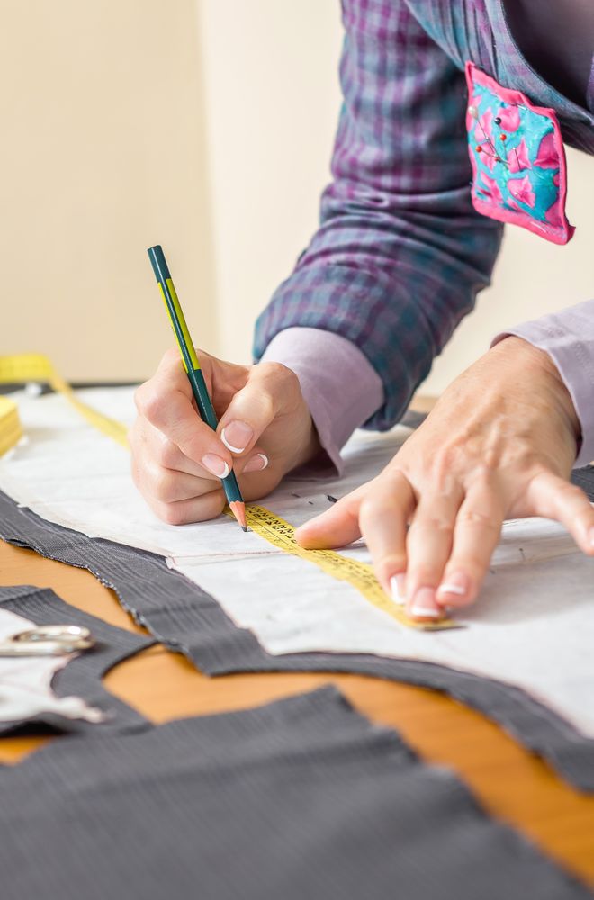 Dressmaker drawing tailor pattern on the table