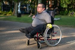 Portrait of man sitting in wheelchair in city park 48eDXb