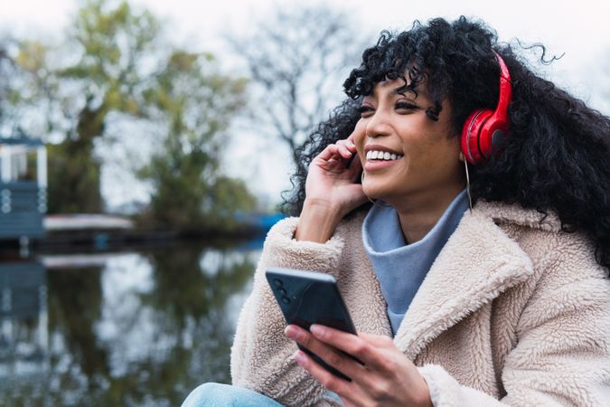 Cheerful Black woman listening to music in lakeside