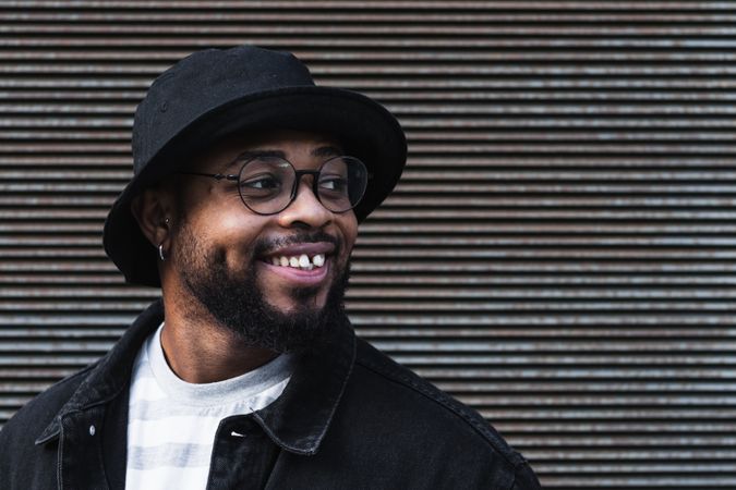 Smiling Black hipster man in hat looking away