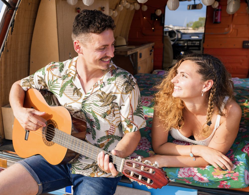 Amorous man plying on guitar and looking at woman in trunk of car