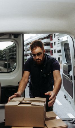 Courier taking out cartons of car for delivery completion