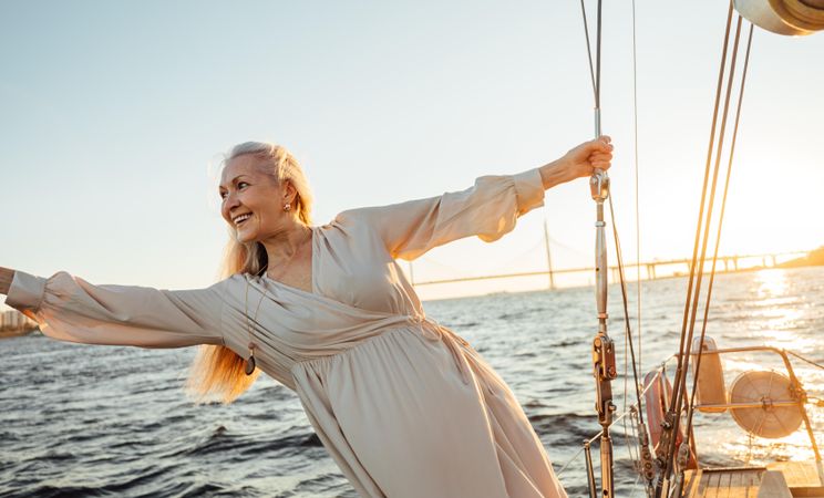 Content woman with long gray hair leaning off lines on a yacht