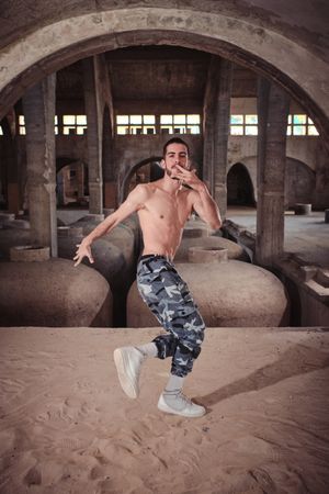 Shirtless man performing break dance in abandoned building