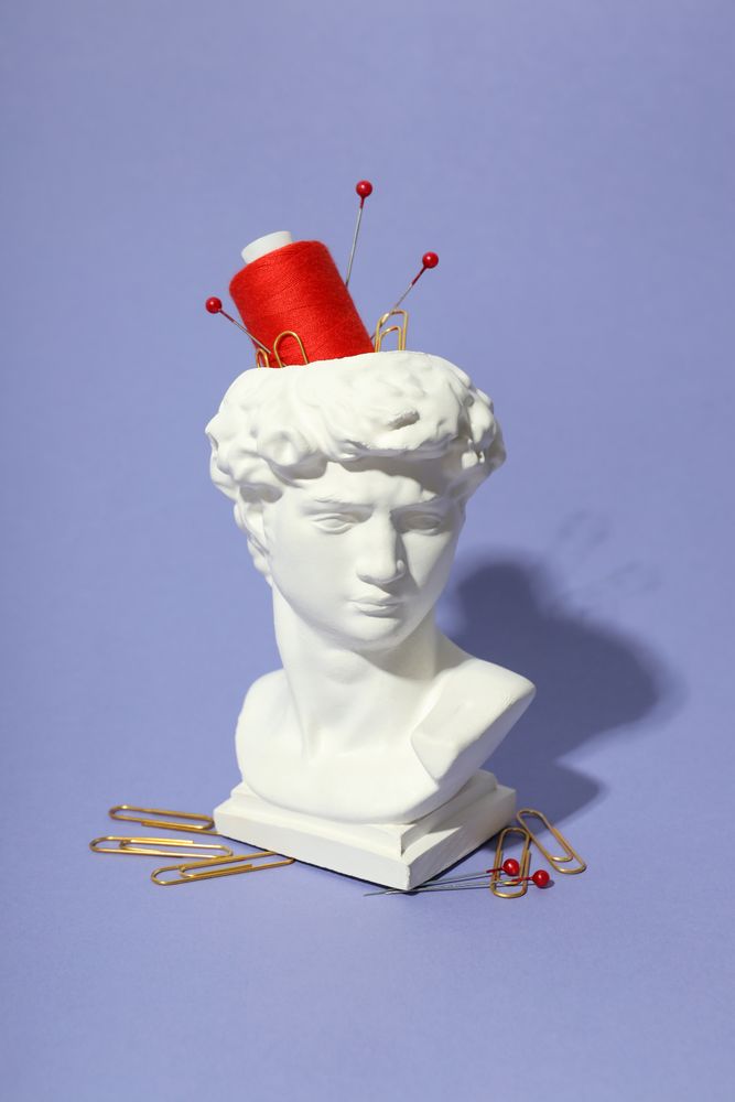 Pins and red spool in bust in purple studio, vertical composition