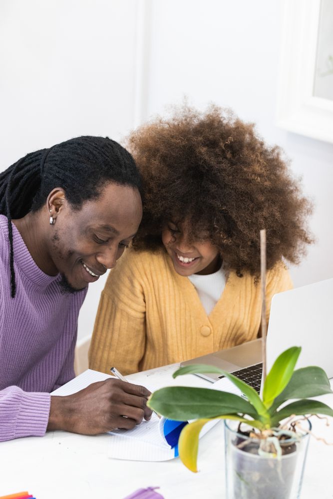 Black father helping daughter with homework on laptop