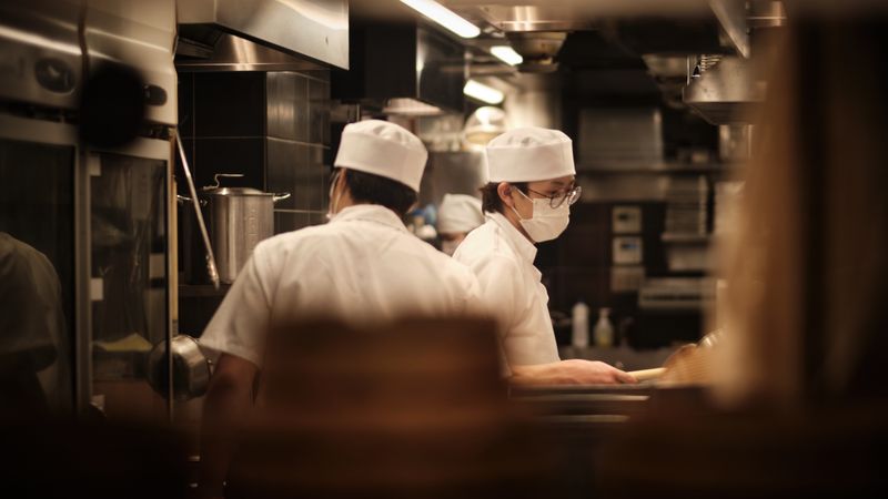 Two restaurant chefs with facemasks in the kitchen