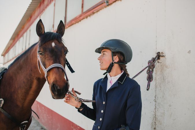 Woman in jockey outfit standing with horse