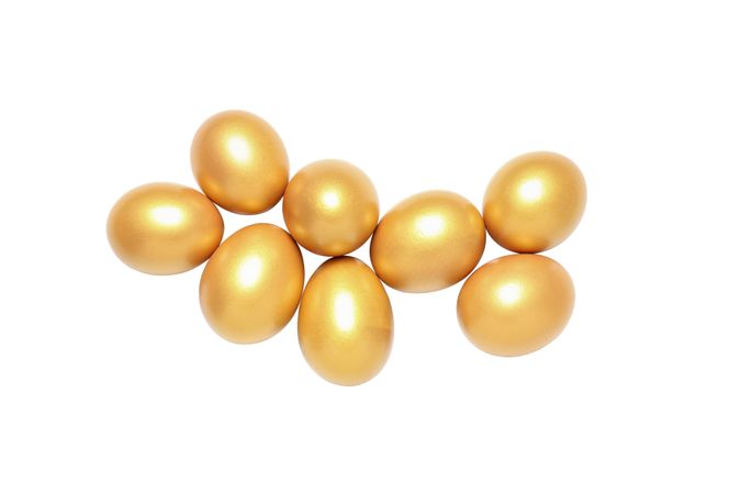 Concept of wealth and retirement - golden eggs, isolated on light background