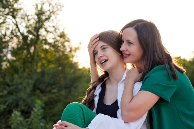 Mom and teenage daughter hugging on walk in park