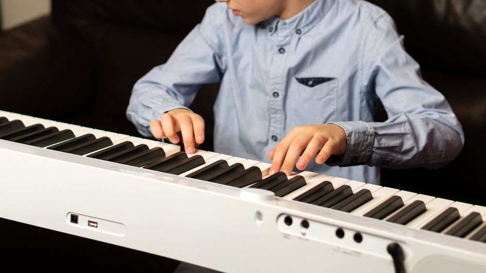 Child playing the keyboard with focused hands and fingers.