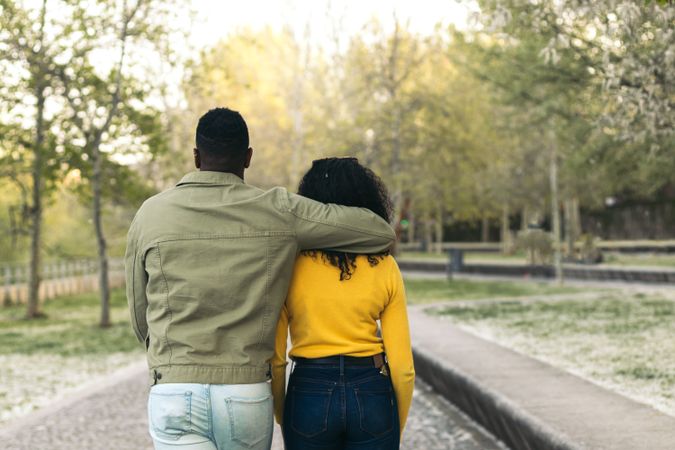 back view of a Black couple walking in a park