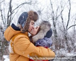 Cute teenage couple holding each other and kissing in wintery forest 429ng5
