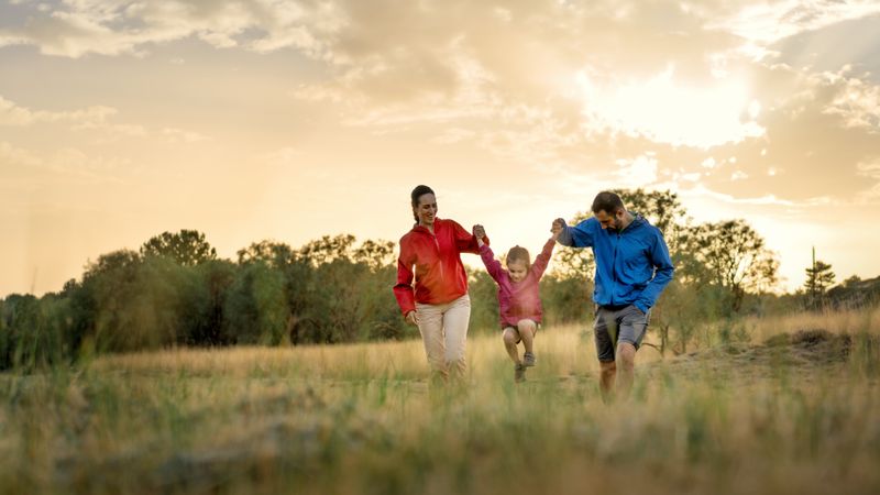 Panoramic banner of a happy family playing in a field at sunset.