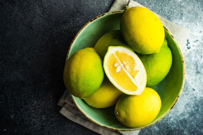 Bowl of fresh lemons with half on top