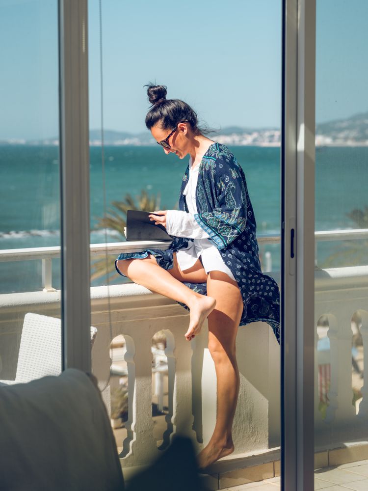 Woman with notepad on balcony in sunny resort