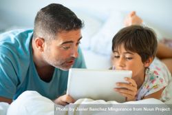 Father with child watching something on tablet in bed 56p7lb