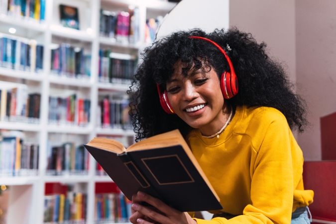 Content female student reading textbook in library