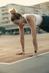 Woman holding a plank pose for core strength and stability during an outdoor fitness workout