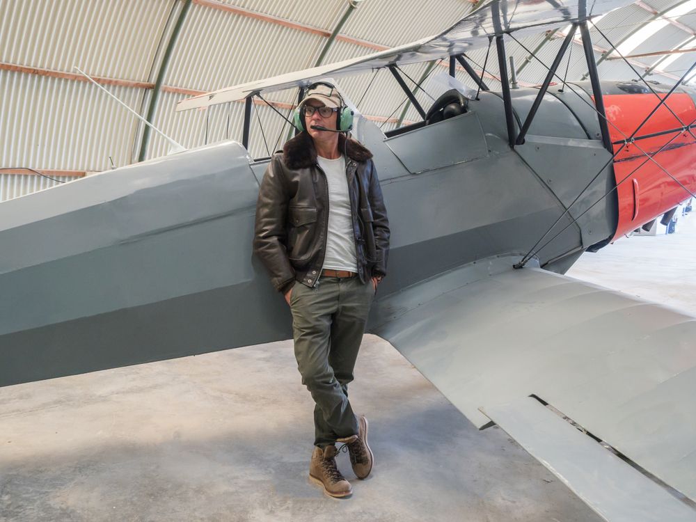 Confident pilot beside retro plane in hangar