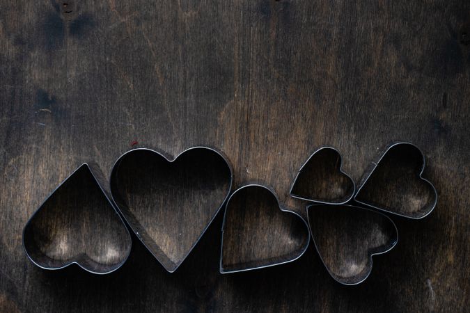 Heart shaped cookie cutters in line on wooden table
