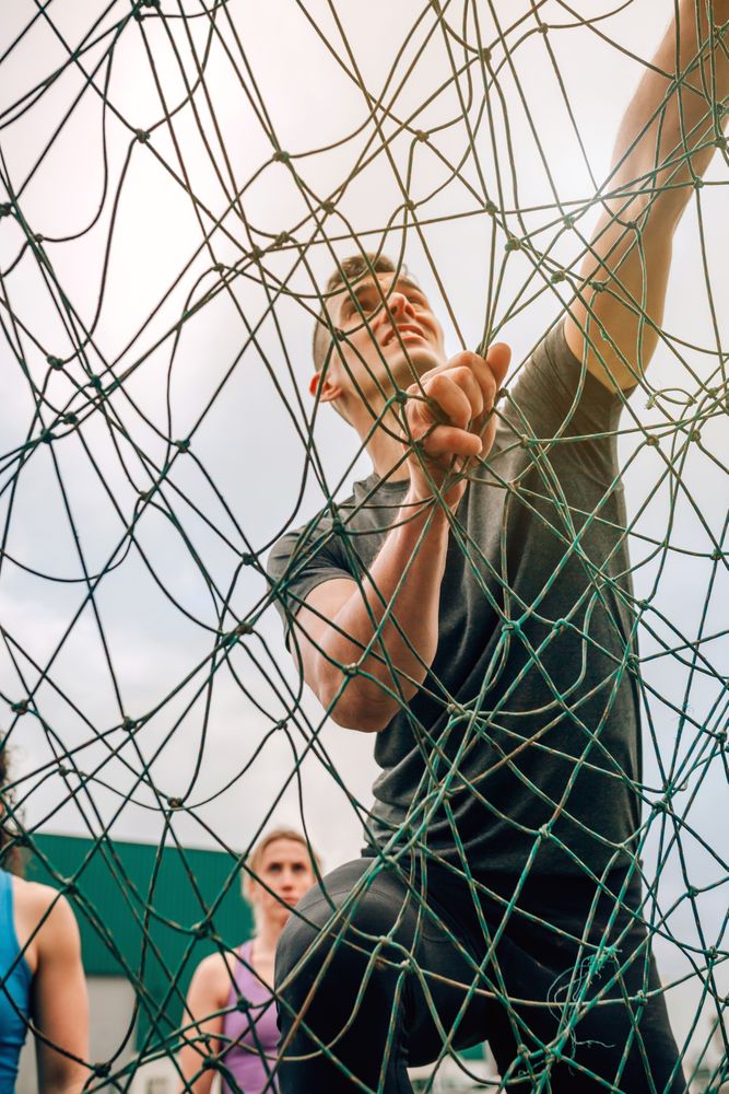 Participant in obstacle course climbing net