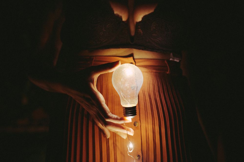 Faceless female with lightbulb in darkness