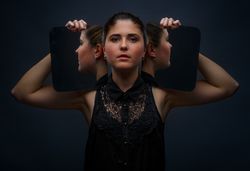 Modern model holding mirrors on sides of face