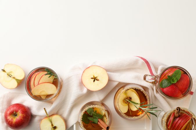 Glasses with apple cider and apples on towel, space for text