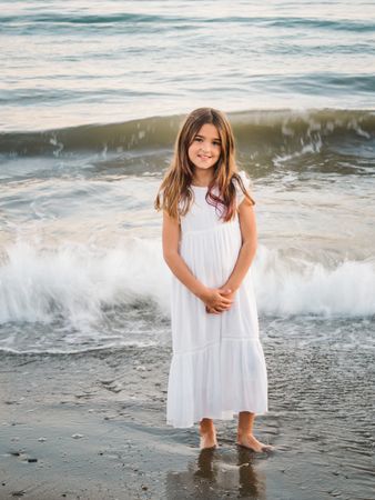 Smiling girl standing on seaside among waves