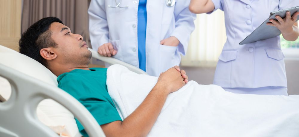 Man in hospital with doctor and nurse at his bed side